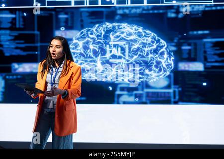 Technician using tablet during presentation, exploring ways emerging AI technologies can enhance businesses. Person at event presents strategies for using artificial intelligence using device Stock Photo