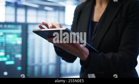 Computer scientist managing data center with advanced technology using digital device. Close up shot of person in server room optimizing data center gear with tablet, camera B Stock Photo