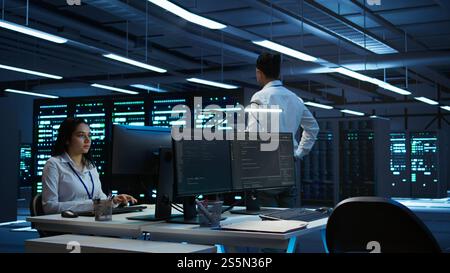 Data center agent providing logistics support to businesses and overseeing infrastructure. Server farm worker oversees hardware rackmounts and communicates with technicians, camera B Stock Photo