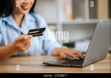 Close-up and selective focus credit card in Womans hands, She holding a credit card while typing on laptop computer Stock Photo