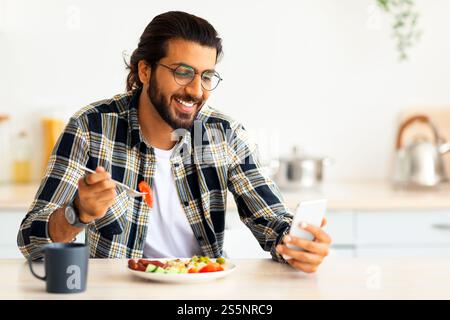 Handsome arab man using cellphone while having breakfast Stock Photo