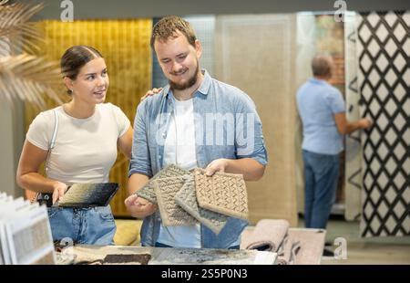 Husband and wife look at samples of carpet fabrics, small pieces of floor pile coverings. Stock Photo