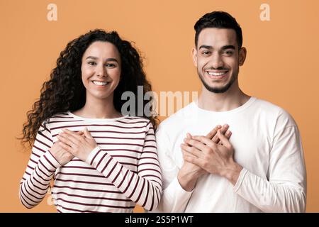 Gratitude Concept. Thankful Middle Eastern Couple Keeping Both Palms On Chest Stock Photo