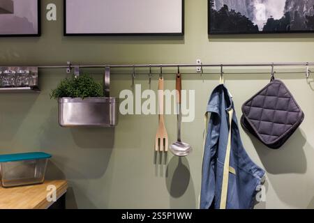 Kitchen set on green wall. Cooking utensils hanging on metal rack in the kitchen. Stock Photo