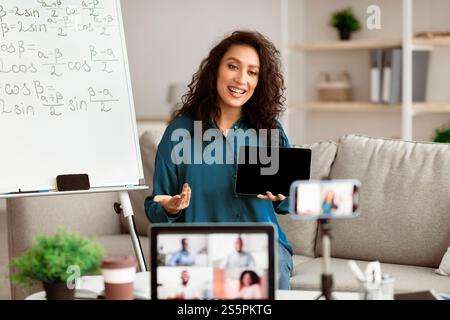 Lady teacher explaining math online showing tablet to computer Stock Photo