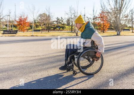 Person using a wheelchair enjoying a sunny day in a park, promoting accessibility and inclusion for people with disabilities Stock Photo