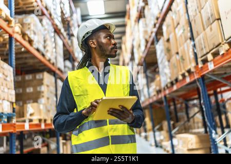Frontal low angle view photo of a warehouse african worker using digital tablet doing inventory Stock Photo