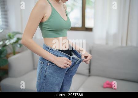 Asian woman dieting Weight loss. Slim woman in oversize jeans . Stock Photo