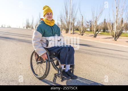 Young person with disability using a wheelchair enjoying a sunny day in a park, promoting inclusion and accessibility Stock Photo