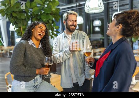 Multi-ethnic friends having fun drinking beer and chatting on an outdoor night bar terrace Stock Photo