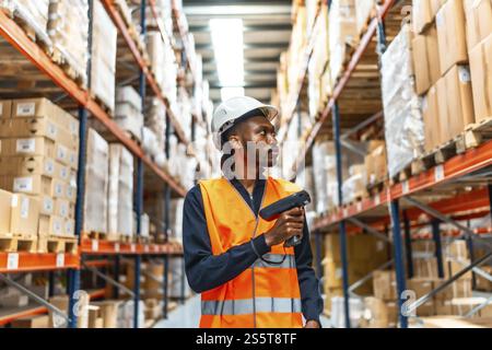 Frontal view of a concentrated african male worker using wireless scanner doing inventory in warehouse Stock Photo