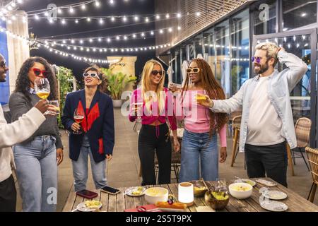Multi-ethnic young group of people drinking standing at bar terrace at night Stock Photo