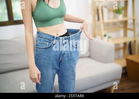 Asian woman dieting Weight loss. Slim woman in oversize jeans . Stock Photo