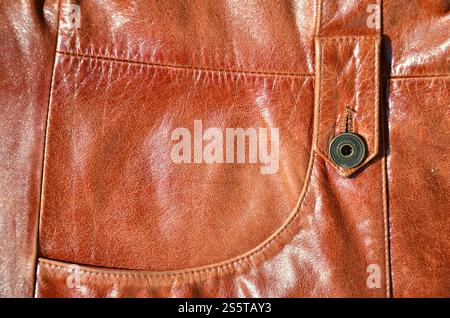 Brown leather texture. Useful as background for any design work. Macro photo of a button on outer clothing made of genuine leather Stock Photo