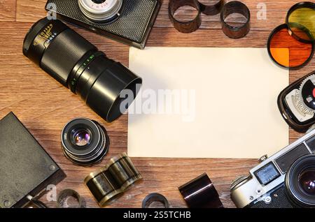 Vintage camera, photography accessories and blank photo frames on wooden table. Still life with copy space. Top view. Retro toned image in beige Stock Photo