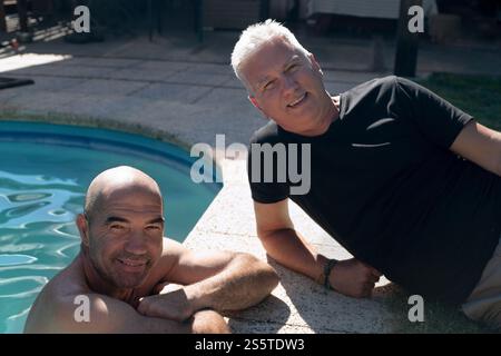Two happy senior men enjoying a sunny day by their home swimming pool Stock Photo