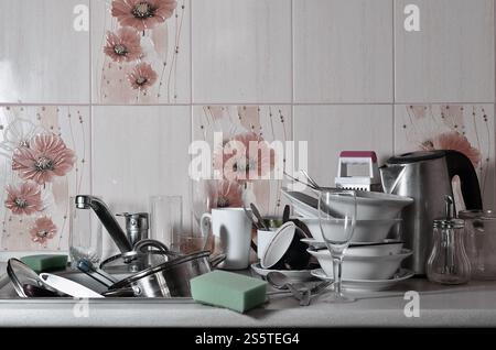 A huge pile of unwashed dishes in the kitchen sink and on the countertop. A lot of utensils and kitchen appliances before washing. The concept of Stock Photo