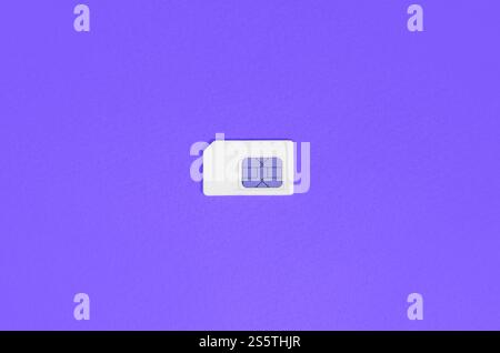 Subscriber identity module. New white SIM card on bright violet color background. Minimal flat lay top view. Subscriber identity module. White SIM Stock Photo