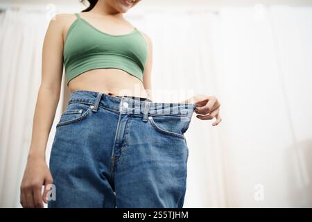 Asian woman dieting Weight loss. Slim woman in oversize jeans . Stock Photo