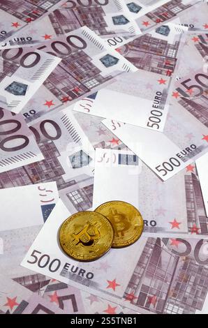 Bitcoins over pile of five hundred euro banknotes. Traditional money versus cryptocurrency concept. Gold coin above 500 euro bills. Close up Stock Photo