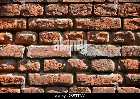 Horizontal wall texture of several rows of very old brickwork made of red brick. Shattered and damaged brick wall with pinched corners Stock Photo
