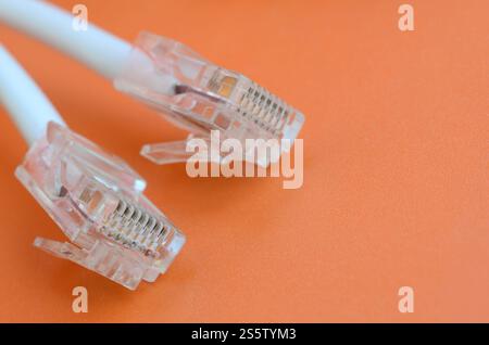 White cord with connector rj45 on a bright orange background. network ethernet cable plugs Stock Photo