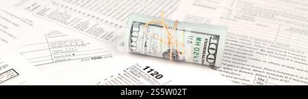 1120 U.S. Corporation income tax return form with roll of american dollar banknotes close up. Concept of tax period in United States Stock Photo