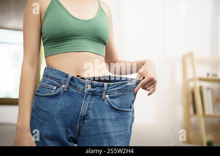 Asian woman dieting Weight loss. Slim woman in oversize jeans . Stock Photo