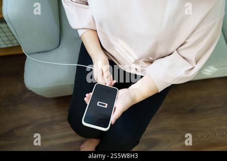 Woman hands Charging mobile phone battery with low battery. plugging a charger in a smart phone with energy bank powerbank power charger Modern Stock Photo
