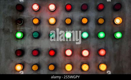 Array of red, green and yellow industrial signal lamp indicators on old and rustic electrical power control center panel Stock Photo
