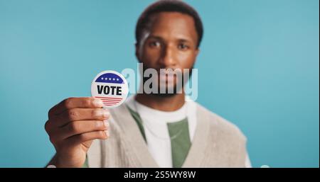 Black man, vote badge and freedom in studio, politics support and message for election registration. Male person, patriotic representative and pin on Stock Photo