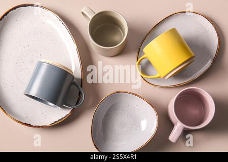 Set of ceramic mugs and plates on grey background Stock Photo