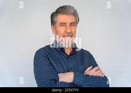 White senior man with beard and arms crossed looking at camera Stock Photo