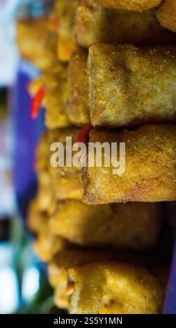 Close-up of stacked, golden-brown fried spring rolls with a blurred background. Stock Photo