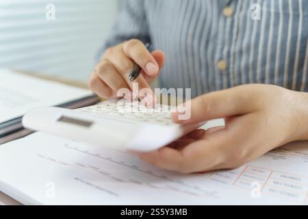 Businesswoman Accountant analyzing investment charts Invoice and pressing calculator buttons over documents. Accounting Bookkeeper Clerk Bank Advisor Stock Photo