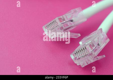 White cord with connector rj45 on a bright pink background. network ethernet cable plugs. White cord with connector rj45 on a bright pink background. Stock Photo