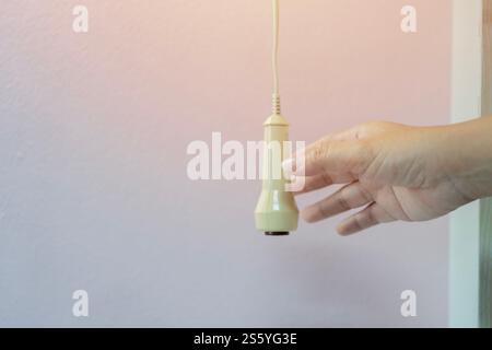 Cropped image of hand hold or pressing emergency nurse call button over white wall background. Selective focus, copy space. Stock Photo