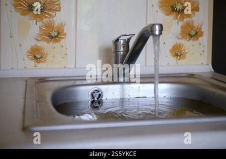 Stainless steel sink plug hole close up full of water and particles of food. Overflowing kitchen sink, clogged drain. Problems with the water supply. Stock Photo
