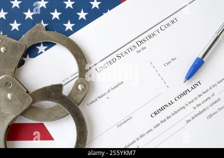 District Court Criminal complaint court papers with handcuffs and blue pen on United States flag close up Stock Photo