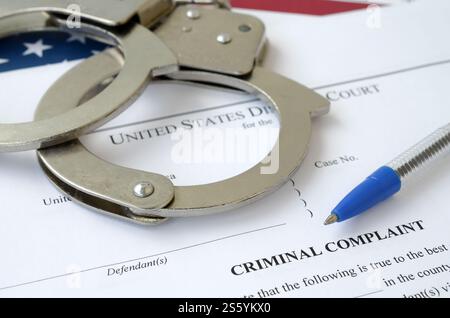 District Court Criminal complaint court papers with handcuffs and blue pen on United States flag close up Stock Photo