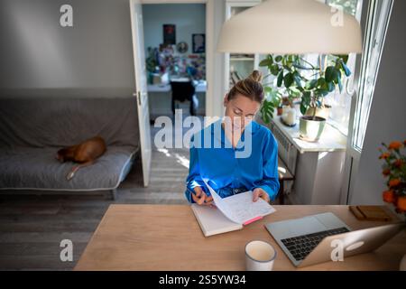 Thoughtful woman of middle age working at laptop from home office. Remote working.  Stock Photo