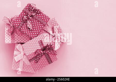 Pile of a small ed gift boxes with ribbons lies on a background. Minimalism flat lay top view. Image toned in Viva Magenta, color of the 2023 year. Stock Photo