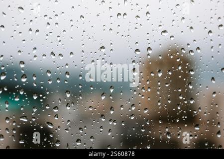 Raindrops on an apartment window. Close up, macro shot, blurred city building in the background, no people. Stock Photo