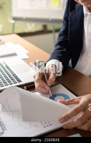 Elderly businessman analyzing data and taking notes in a modern office setting Stock Photo