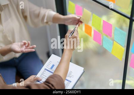 Business People working on sticky notes creative writing down ideas on post it notes professional investor start up project business Stock Photo