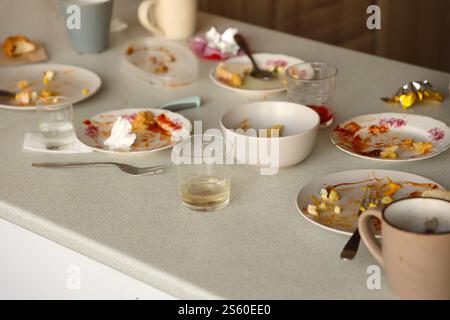 Empty dirty plates with spoons and forks on the table after meal. Banquet ending concept. Unwashed dishes ready to cleaning. Empty dirty plates with Stock Photo