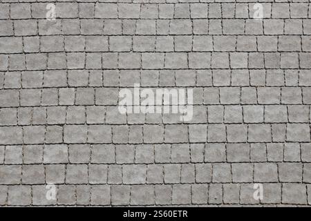 Gray color paving slabs in the pedestrian street sidewalk. Rough cobblestone pattern with many square shaped stones close up. Gray color paving slabs Stock Photo