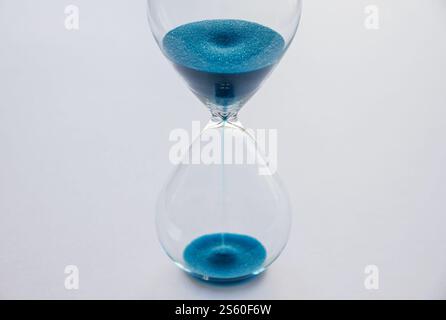 Hourglass containing blue sand isolated on white background. Concept of time passing. Hourglass containing blue sand isolated on white background Stock Photo