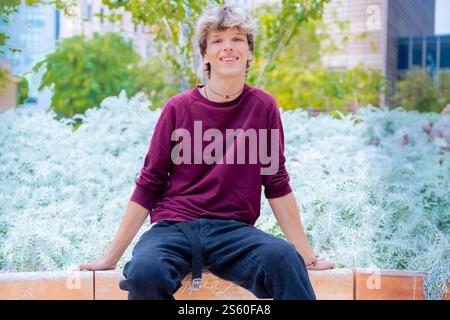 Smiling Young Man Sitting on a Bench in an Urban Park Stock Photo