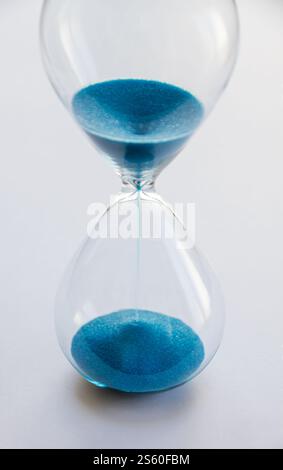 Hourglass containing blue sand isolated on white background. Concept of time passing. Hourglass containing blue sand isolated on white background Stock Photo